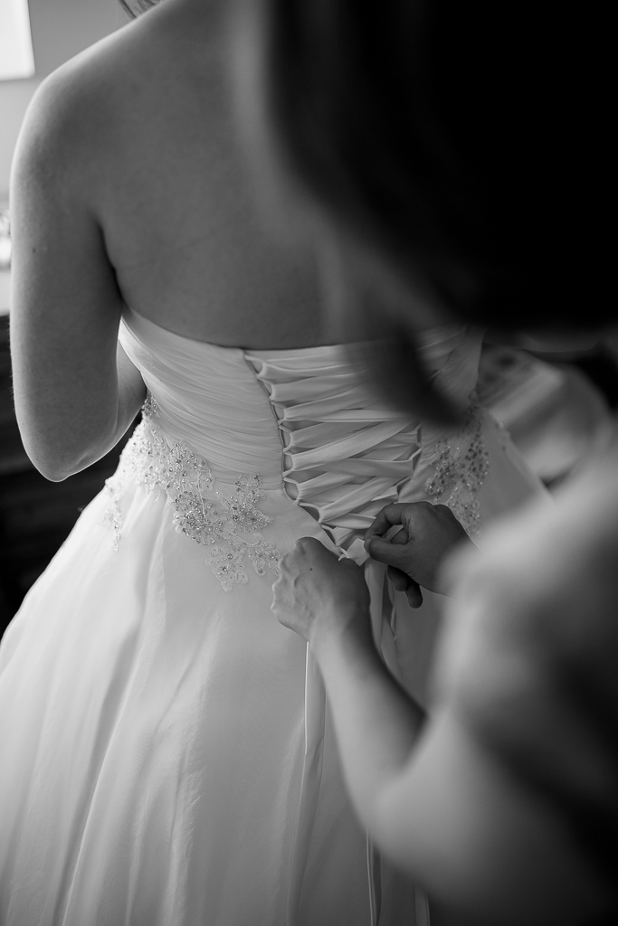 Belle photo au moment d'enfilez la robe de la mariée