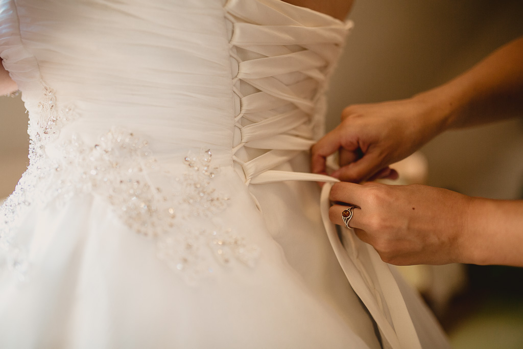 Photographe capture le moment d'enfilez la robe de la mariée