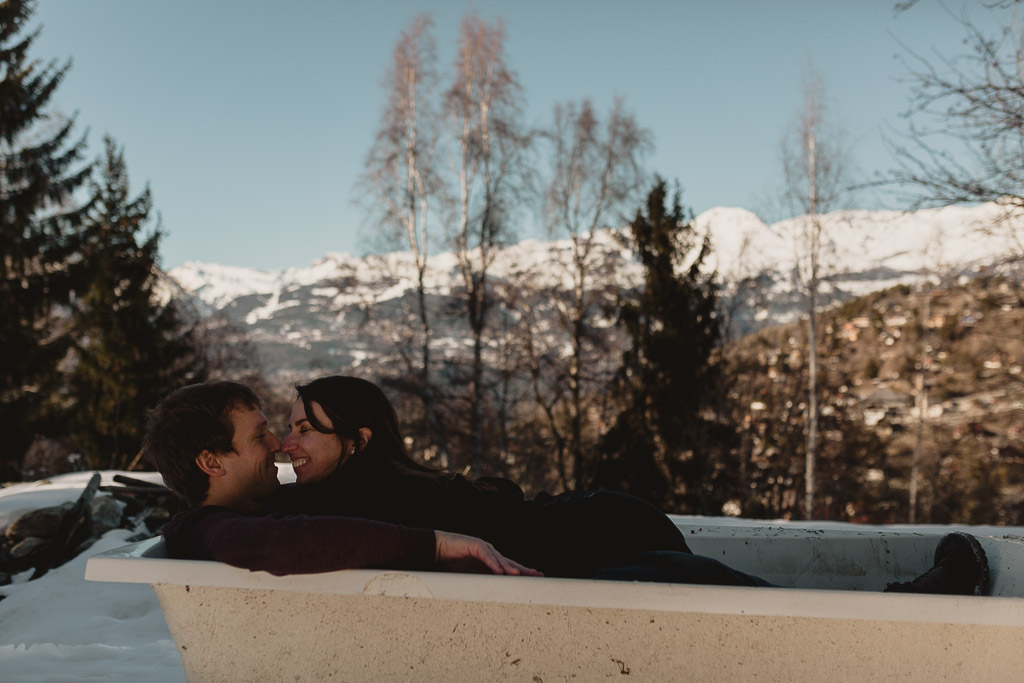 Photographer in Switzerland - Snow photoshoot bath tub Couple in a lountain village alps