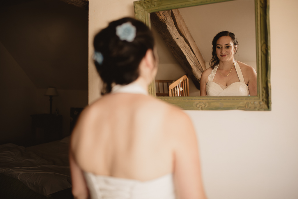 la photographe capture la mariée qui se prépare pour se regarder au miroir