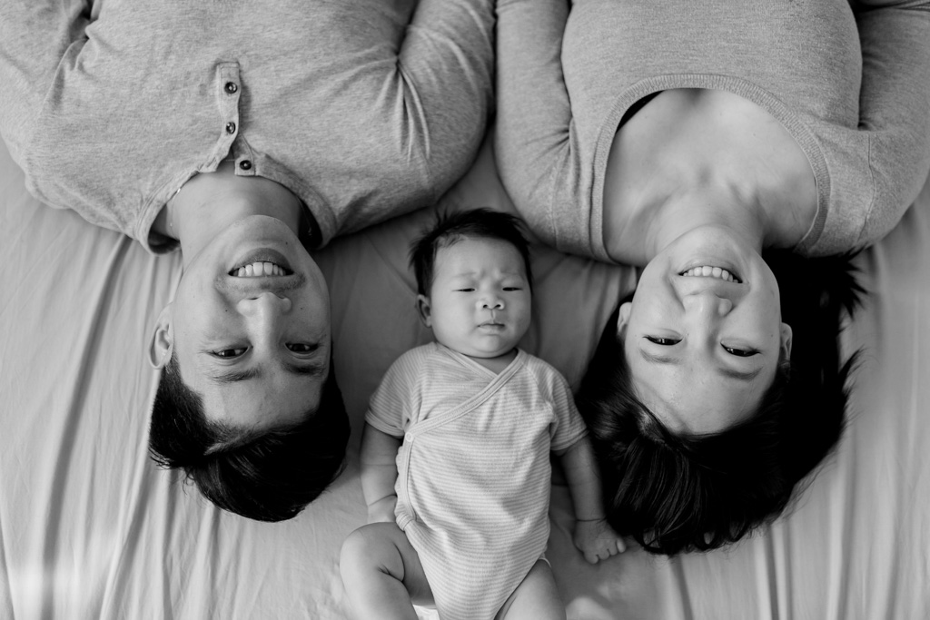 Parents allongés au lit avec leur bébé d'un mois à Vincennes