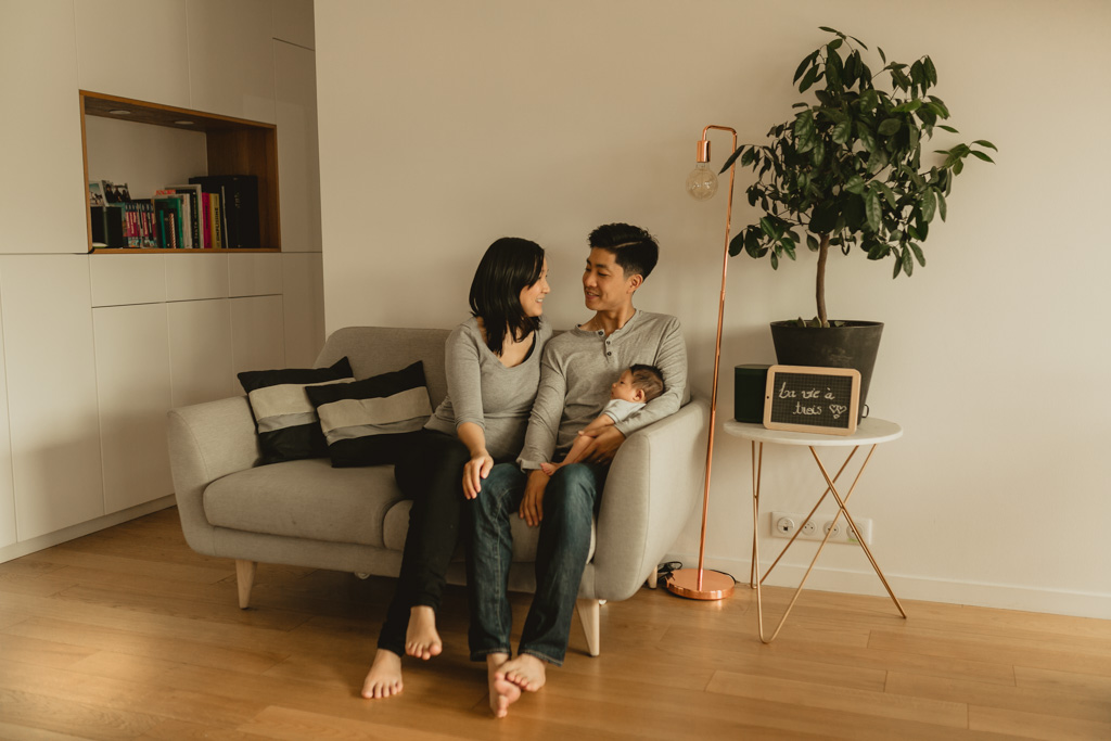 Parents se regardant assis sur le canapé lors d’une séance naissance à domicile Paris