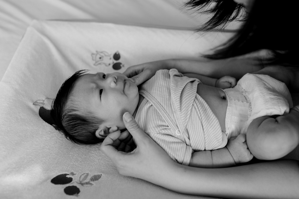 Bébé sur la table à langer avec les mains de la maman qui fait des câlins
