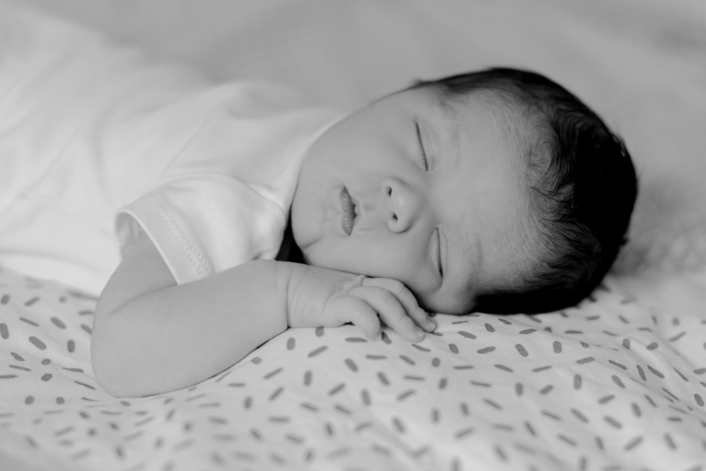 Bébé qui dort sur le lit des parents, photo rapprochée du visage, séance naissance à domicile à Saint-Maur