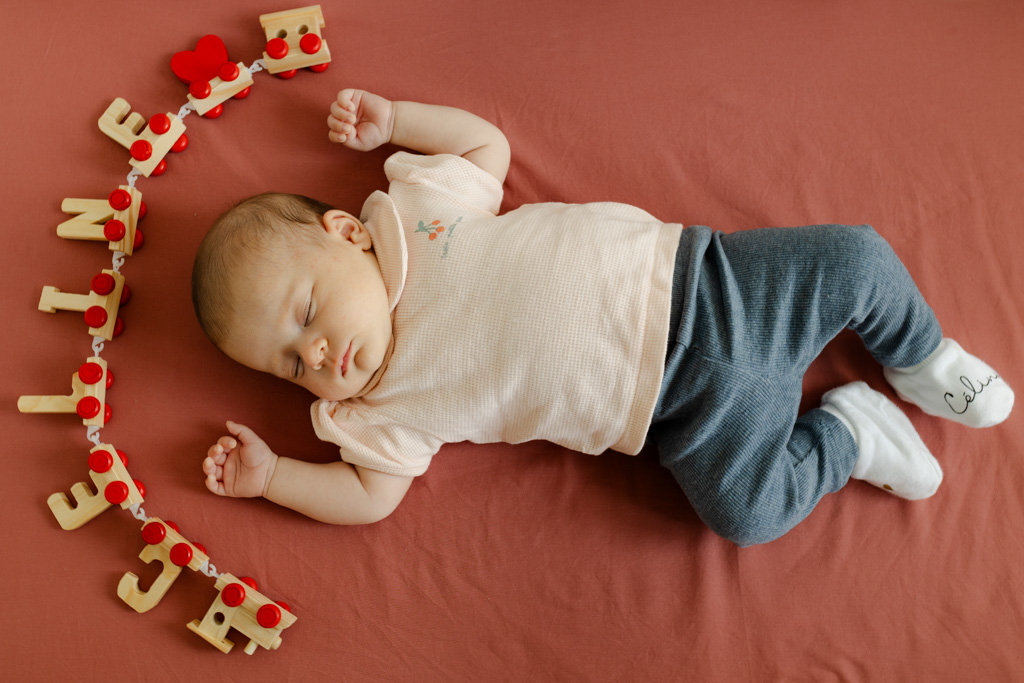 Bébé d’un mois qui dort paisiblement dans son berceau avec son prénom visible, séance à domicile à Paris