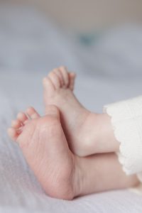 Photo en gros plan des pieds d’un nouveau-né réalisée à domicile pendant une séance photo de naissance, mettant en valeur les petits détails du bébé