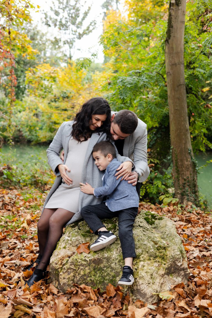 Maman enceinte avec son aîné qui touche son ventre, papa derrière eux, lors d'une mini séance photo d'automne à l'île Sainte-Catherine