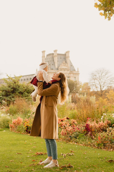 Maman qui joue avec sa fille en automne aux jardins des Tuileries, la lance en l’air et la rattrape avec tendresse